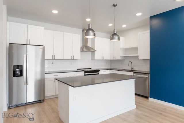 2221F Willow Unit 104, Livingston, MT 59047 - kitchen featuring stainless steel appliances, a sink, wall chimney range hood, light wood-type flooring, and a kitchen island