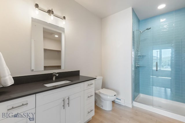 2221F Willow Unit 104, Livingston, MT 59047 - full bathroom featuring a stall shower, baseboard heating, toilet, vanity, and wood finished floors