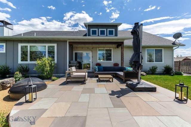 rear view of house with an outdoor living space with a fire pit and a patio area