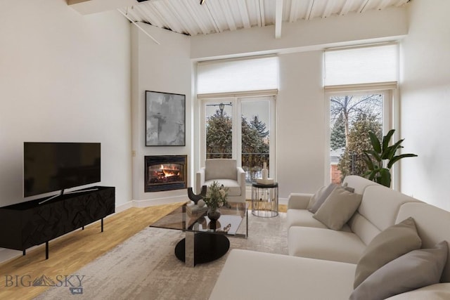 living room with a towering ceiling, light hardwood / wood-style flooring, and beamed ceiling