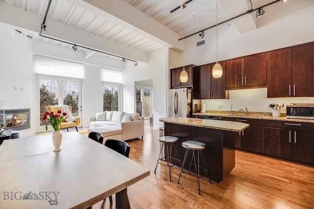 kitchen featuring a breakfast bar, a center island, decorative light fixtures, light hardwood / wood-style floors, and stainless steel appliances