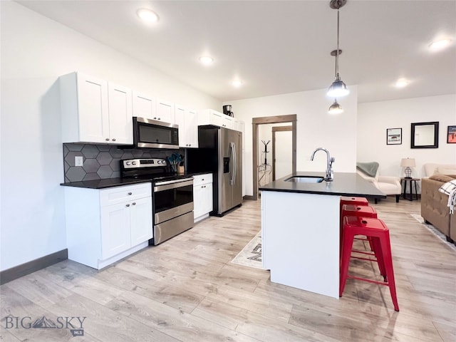 kitchen featuring sink, decorative light fixtures, a breakfast bar area, white cabinets, and appliances with stainless steel finishes