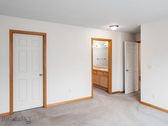 unfurnished bedroom with ensuite bath, sink, and light colored carpet