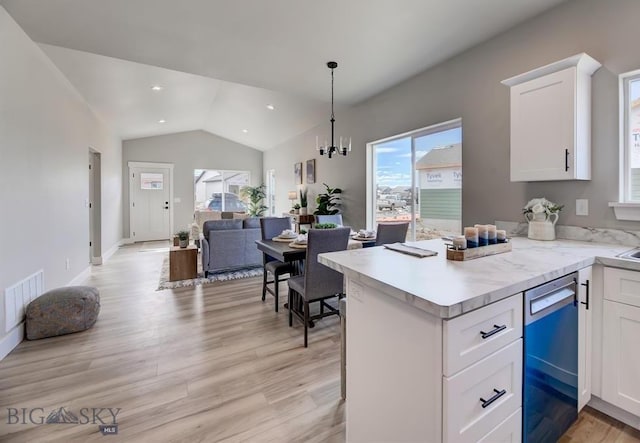 kitchen with white cabinetry, dishwasher, hanging light fixtures, light hardwood / wood-style floors, and vaulted ceiling