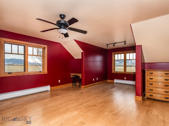 additional living space featuring lofted ceiling, baseboards, a baseboard heating unit, and wood finished floors