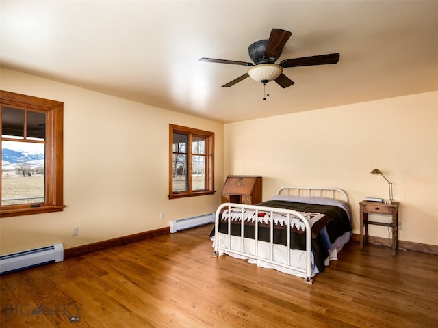 bedroom with baseboards, a baseboard heating unit, baseboard heating, and wood finished floors