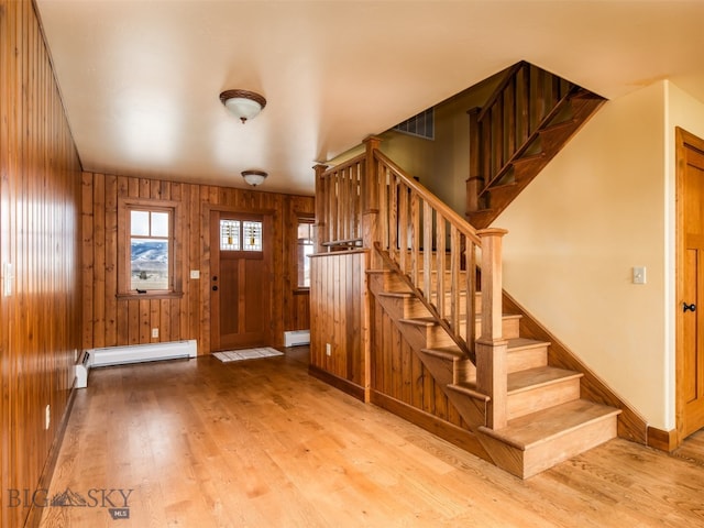 foyer entrance featuring baseboard heating, wood finished floors, and wooden walls