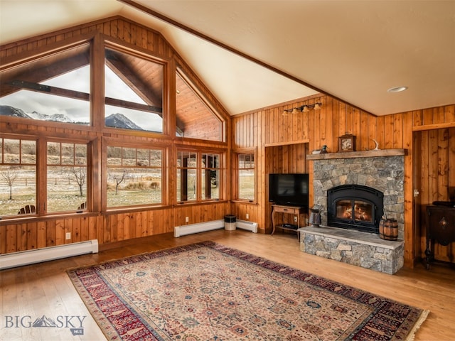 living area featuring lofted ceiling, wooden walls, a baseboard heating unit, a fireplace, and wood-type flooring