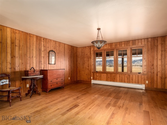 interior space featuring a baseboard heating unit, wood walls, wood finished floors, and a chandelier