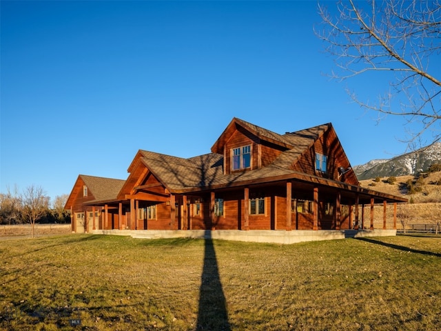 back of house with a mountain view and a yard