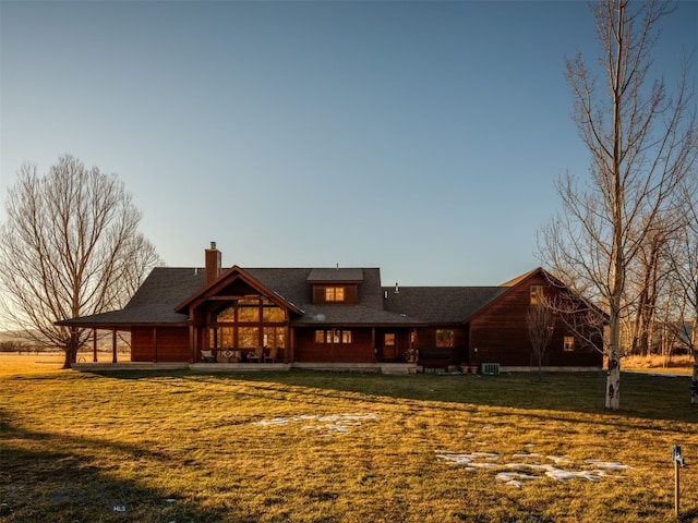 rear view of house featuring central air condition unit, a chimney, and a lawn