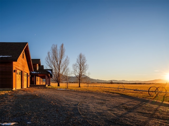 yard at dusk featuring a rural view and a mountain view