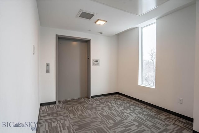 carpeted empty room featuring elevator