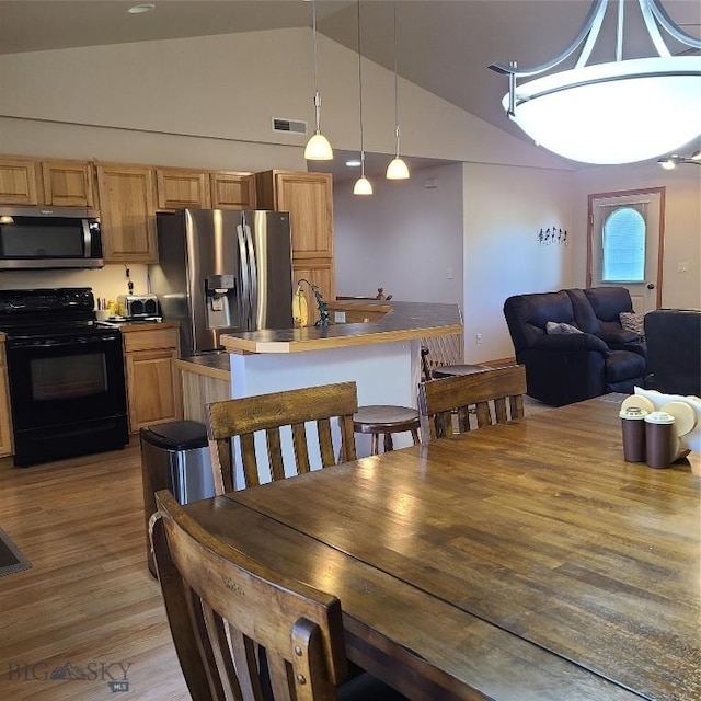 dining area featuring light hardwood / wood-style floors and vaulted ceiling