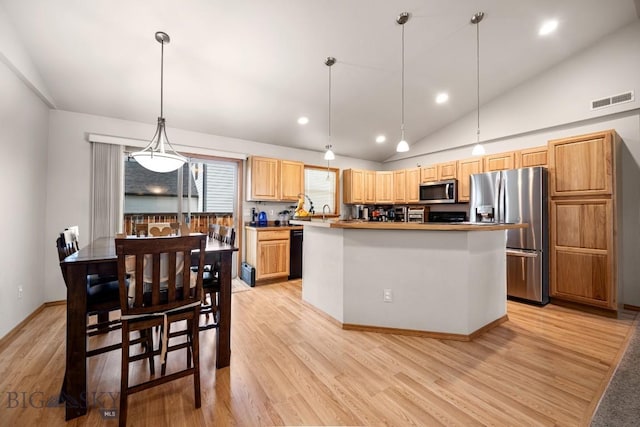1311 Cruiser Ln, Belgrade, MT 59714 - kitchen featuring appliances with stainless steel finishes, lofted ceiling, light wood-style flooring, a kitchen island, and decorative light fixtures