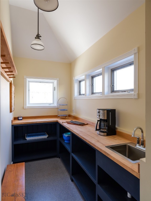 kitchen with wood counters, blue cabinets, sink, and lofted ceiling