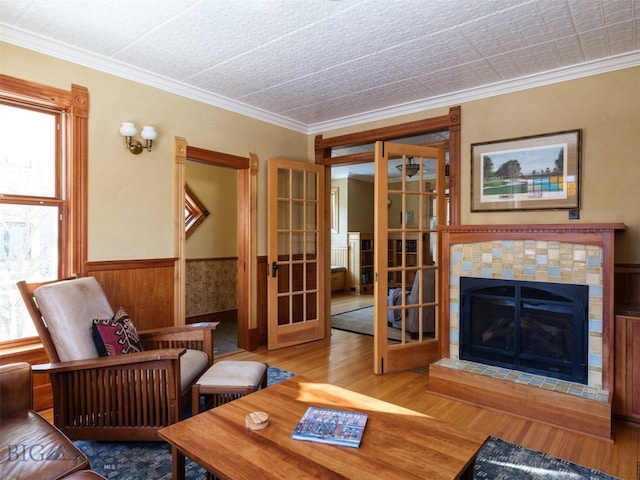 living room with hardwood / wood-style floors, french doors, crown molding, and a tiled fireplace