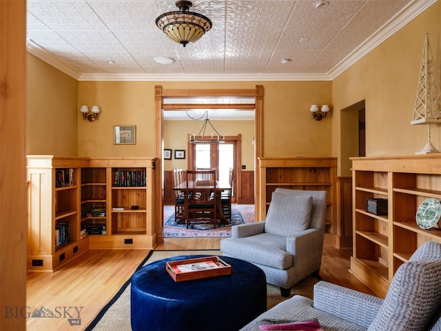 living area featuring a wainscoted wall, crown molding, and wood finished floors