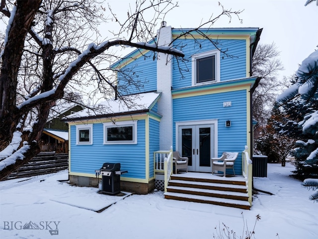 snow covered house featuring french doors