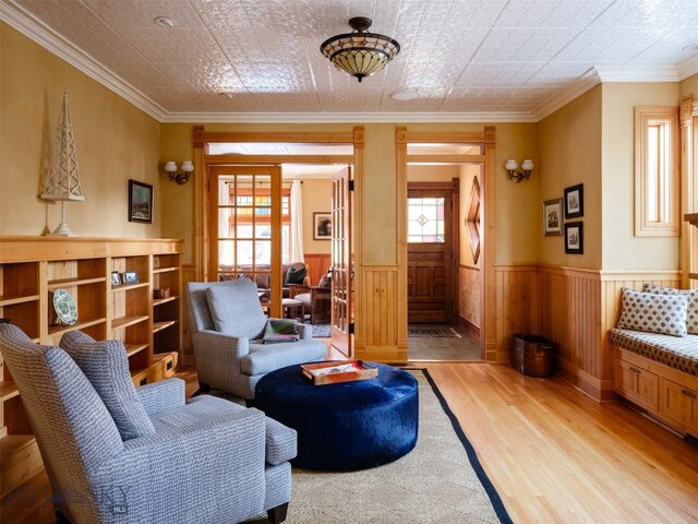 living area with light hardwood / wood-style flooring and ornamental molding