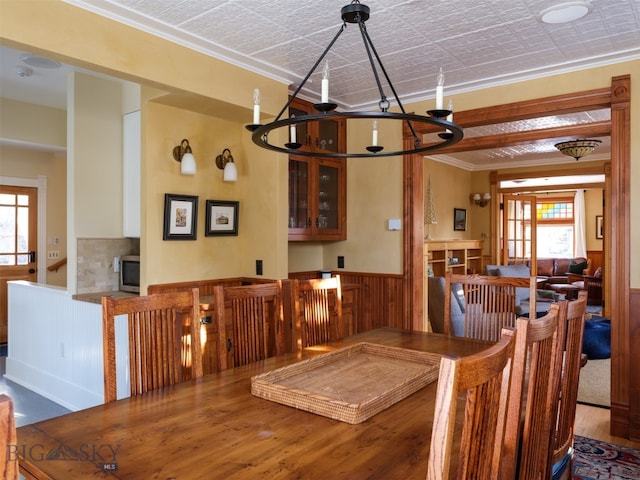 dining area featuring hardwood / wood-style floors, wooden walls, an inviting chandelier, and crown molding