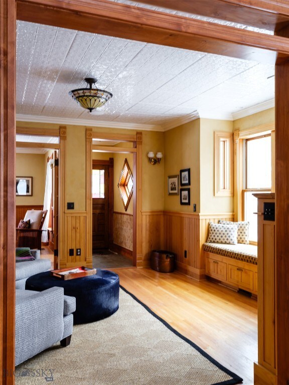 living room featuring hardwood / wood-style flooring, ornamental molding, and wood walls