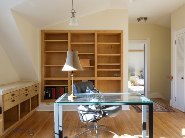 home office featuring built in shelves, light hardwood / wood-style flooring, and lofted ceiling