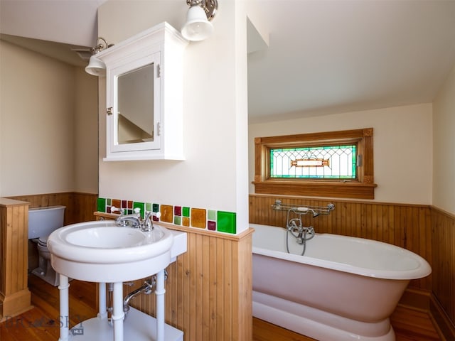 bathroom featuring wood-type flooring, toilet, a bathtub, and sink