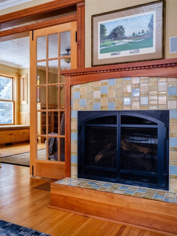 interior details with a tile fireplace, hardwood / wood-style flooring, and ornamental molding