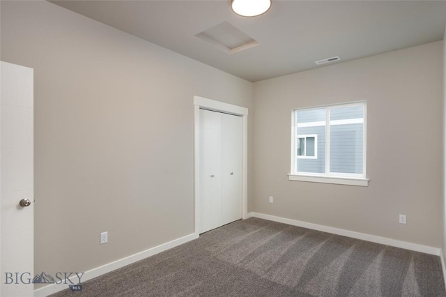 unfurnished bedroom with dark colored carpet, a closet, visible vents, and baseboards