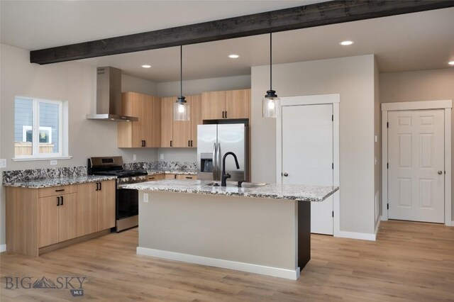 kitchen featuring light stone countertops, pendant lighting, appliances with stainless steel finishes, wall chimney exhaust hood, and a kitchen island with sink