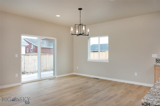 unfurnished dining area with light wood-type flooring and a notable chandelier