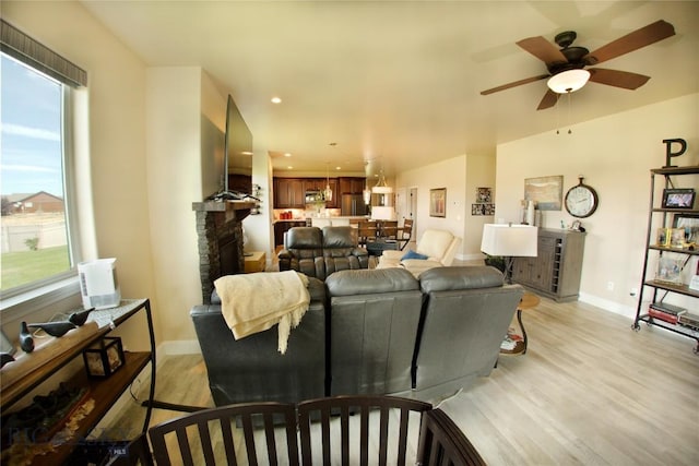 living area with light wood-type flooring, ceiling fan, baseboards, and recessed lighting