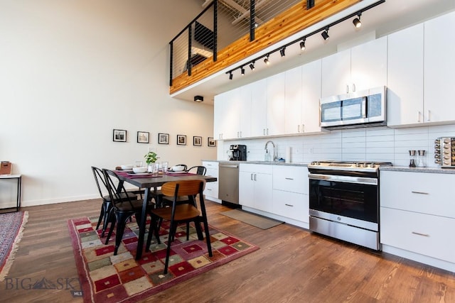 kitchen with white cabinets, appliances with stainless steel finishes, and dark wood-type flooring