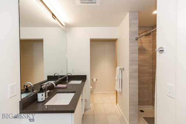 bathroom with tile patterned floors, toilet, vanity, and tiled shower