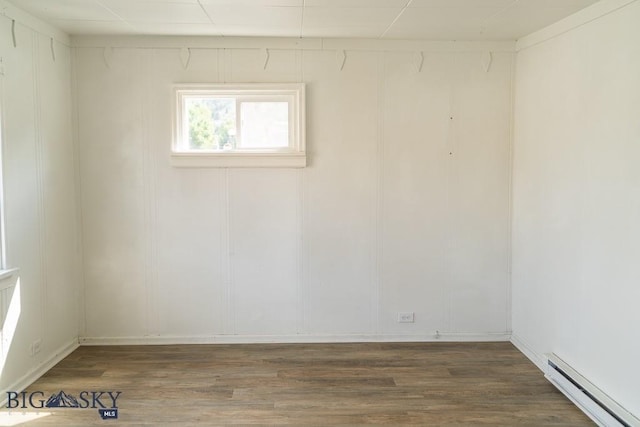 spare room with a baseboard radiator and dark wood-type flooring