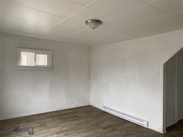 unfurnished room featuring baseboard heating and dark hardwood / wood-style floors