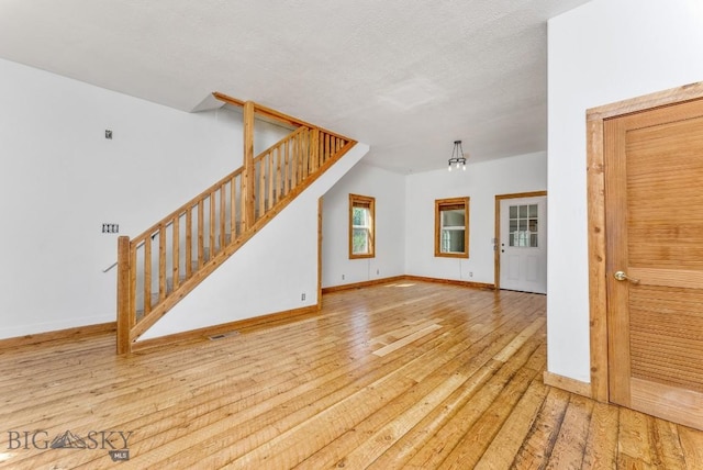 unfurnished living room featuring light wood-type flooring and a textured ceiling