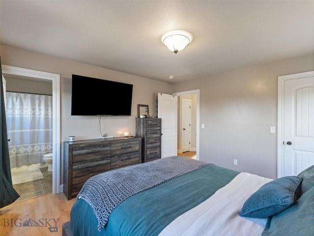 bedroom with light wood-type flooring and ensuite bath