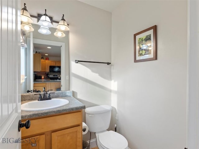 bathroom with decorative backsplash, vanity, and toilet