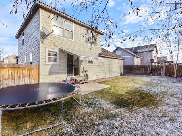 back of house featuring a lawn, a trampoline, and a patio