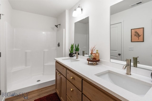 bathroom featuring hardwood / wood-style flooring, vanity, and walk in shower