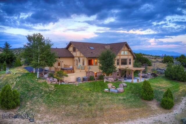 back house at dusk with a lawn and a deck with mountain view