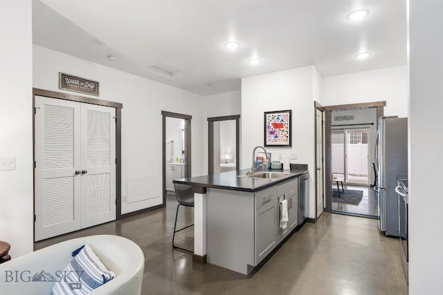 kitchen with sink, kitchen peninsula, a kitchen bar, gray cabinets, and appliances with stainless steel finishes