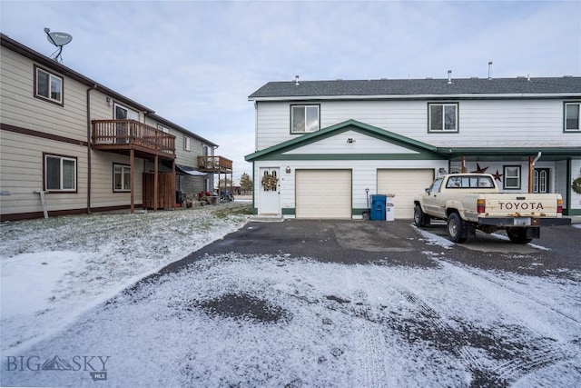 snow covered house with a garage and a deck