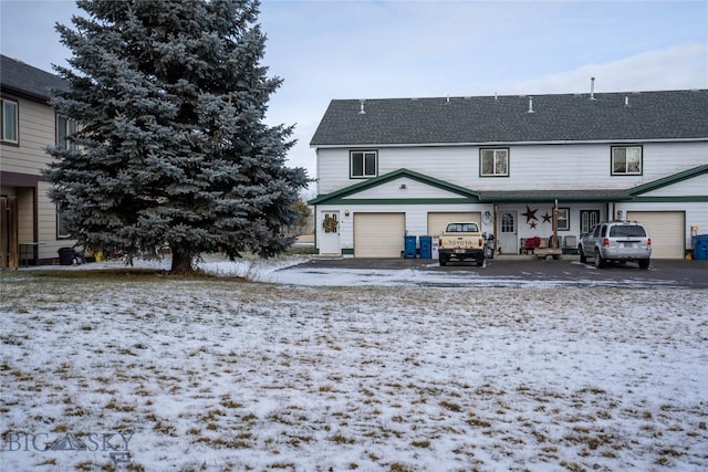 snow covered back of property with a garage