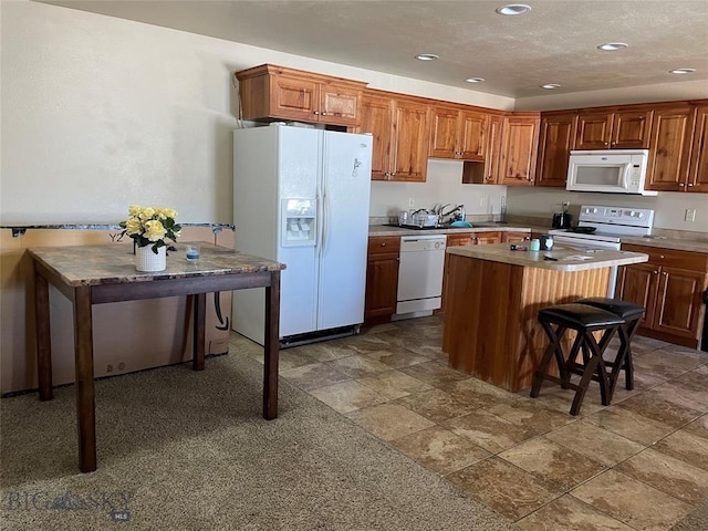 kitchen featuring a kitchen island, sink, white appliances, and a breakfast bar area