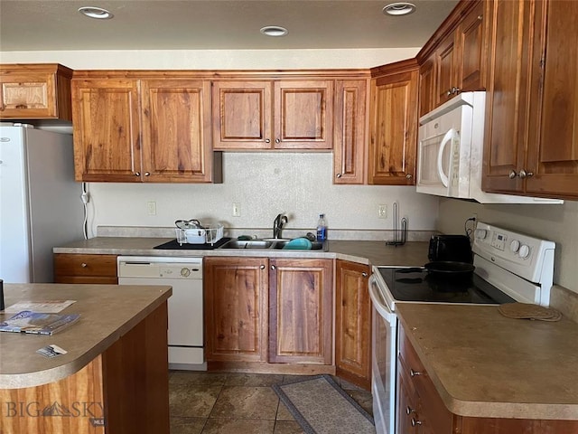 kitchen with white appliances, dark tile patterned flooring, and sink