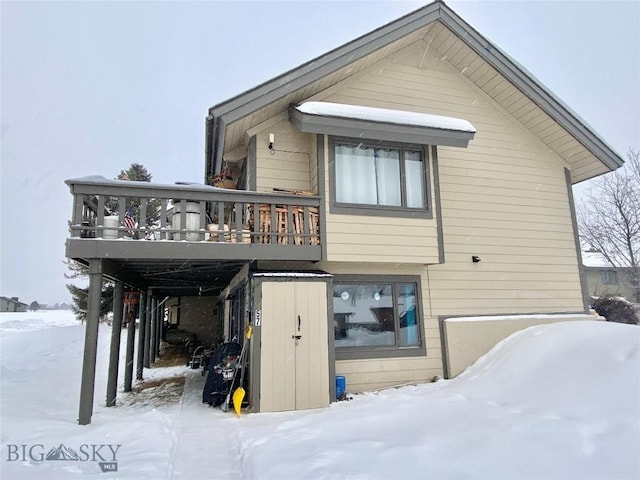 snow covered back of property with a deck