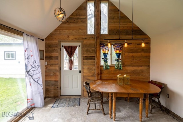 dining area with wood walls, lofted ceiling, and concrete floors